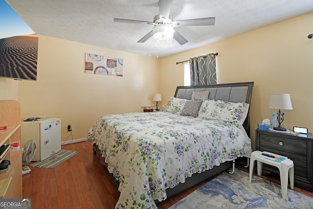 bedroom with dark wood-style floors, ceiling fan, baseboards, and a textured ceiling