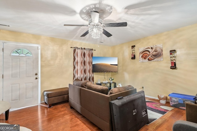 living area with a ceiling fan, visible vents, baseboards, and wood finished floors