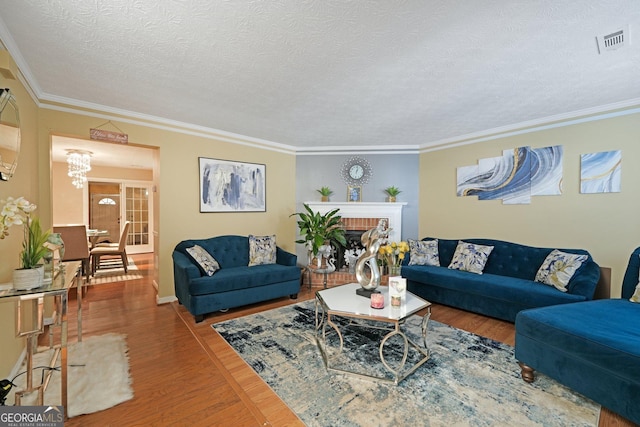 living area featuring ornamental molding, visible vents, a fireplace, and wood finished floors