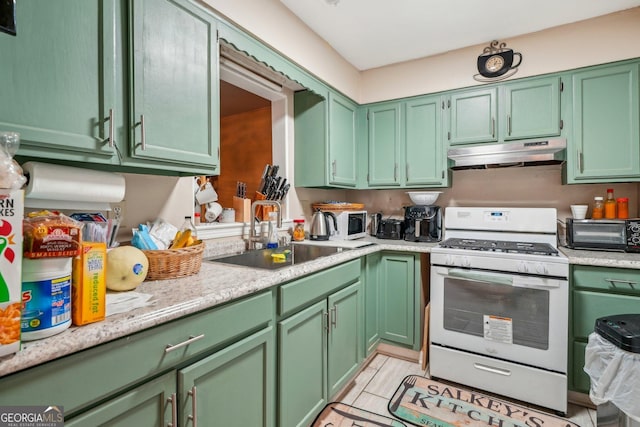 kitchen featuring green cabinets, white gas range oven, a sink, and under cabinet range hood