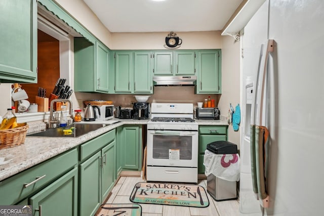 kitchen with white appliances, green cabinetry, a sink, and under cabinet range hood