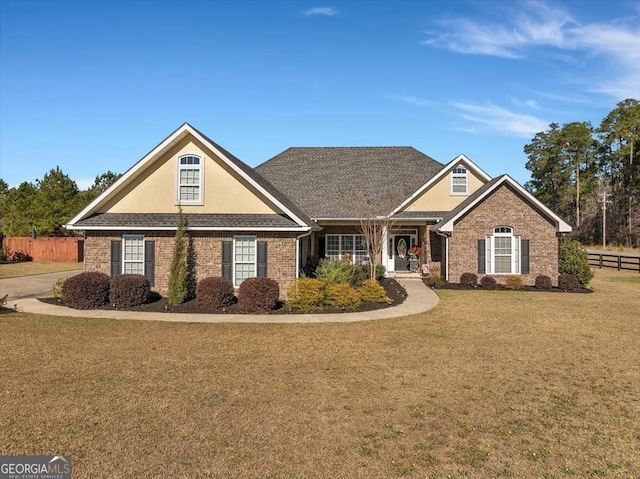 view of front of house featuring a front lawn, fence, and brick siding