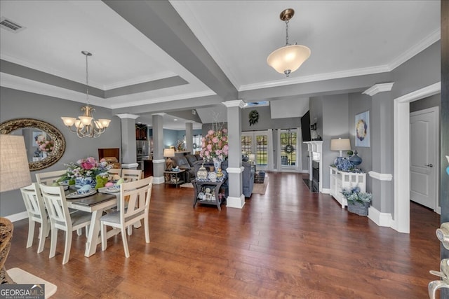 dining space featuring dark wood finished floors, visible vents, ornamental molding, a chandelier, and ornate columns