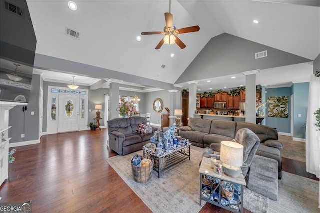 living room with high vaulted ceiling, dark wood-type flooring, visible vents, and ornate columns