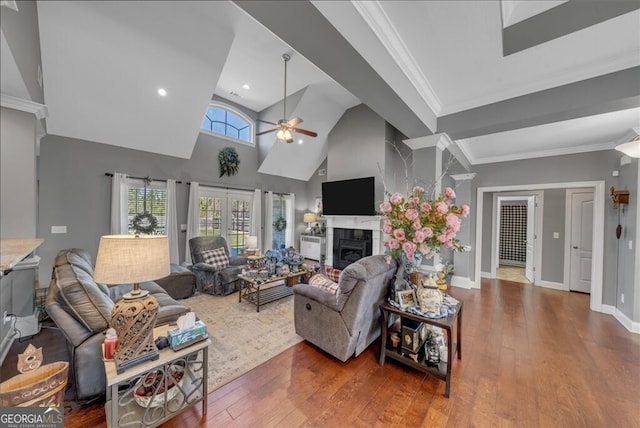 living room with ceiling fan, a fireplace, crown molding, and wood finished floors