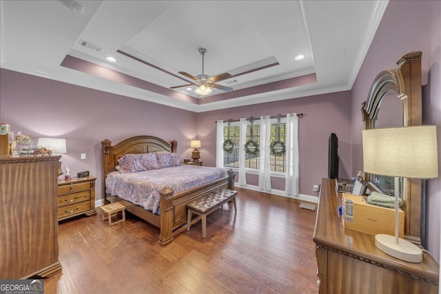 bedroom with a raised ceiling, visible vents, ornamental molding, wood finished floors, and baseboards