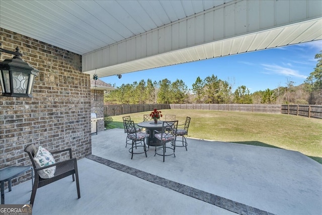 view of patio with outdoor dining space, grilling area, and a fenced backyard