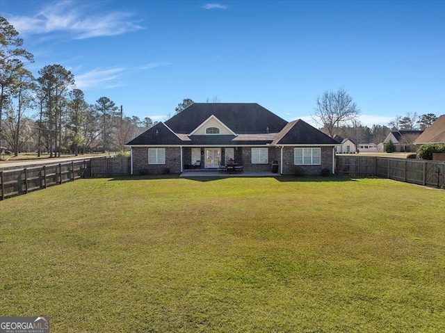 view of front facade with a fenced backyard, brick siding, and a front lawn