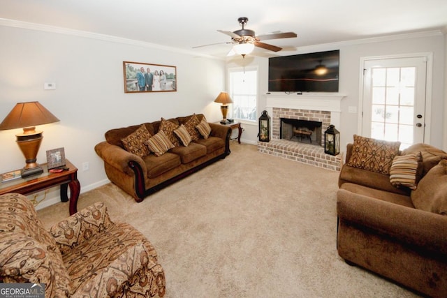 carpeted living room with a brick fireplace, ceiling fan, baseboards, and crown molding