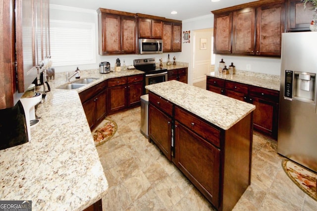 kitchen featuring a center island, crown molding, stainless steel appliances, a sink, and light stone countertops