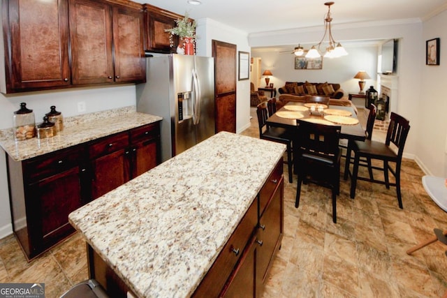 kitchen with light stone counters, open floor plan, a kitchen island, and stainless steel refrigerator with ice dispenser