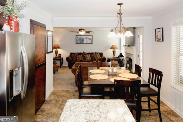 dining space with crown molding, a fireplace, baseboards, and ceiling fan