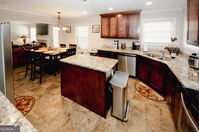 kitchen with a kitchen island, light stone countertops, stainless steel appliances, pendant lighting, and a sink