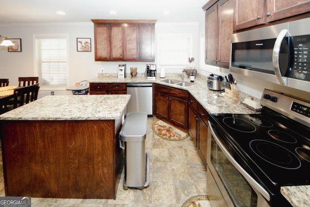 kitchen with a sink, a center island, ornamental molding, appliances with stainless steel finishes, and light stone countertops