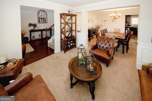 living room featuring stairway, an inviting chandelier, ornamental molding, wainscoting, and carpet flooring