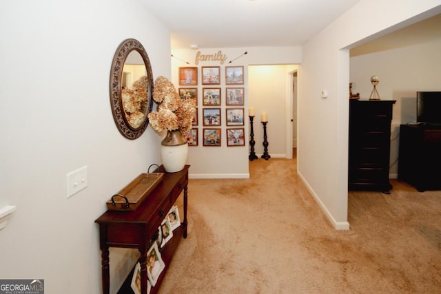 hall featuring baseboards and light colored carpet