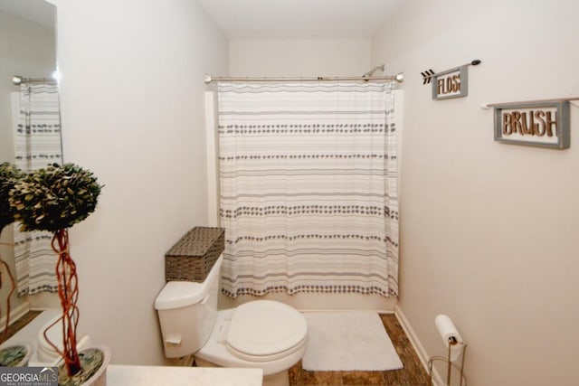 full bath featuring shower / tub combo, toilet, and baseboards