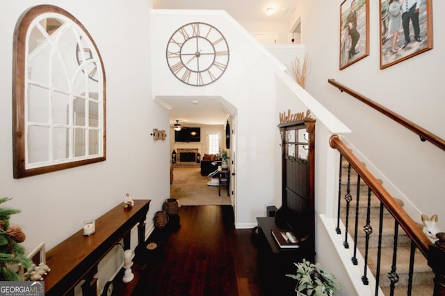 corridor featuring arched walkways, stairway, and dark wood-style flooring