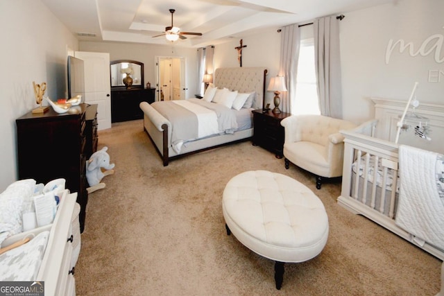 bedroom featuring a raised ceiling, visible vents, ceiling fan, and light carpet