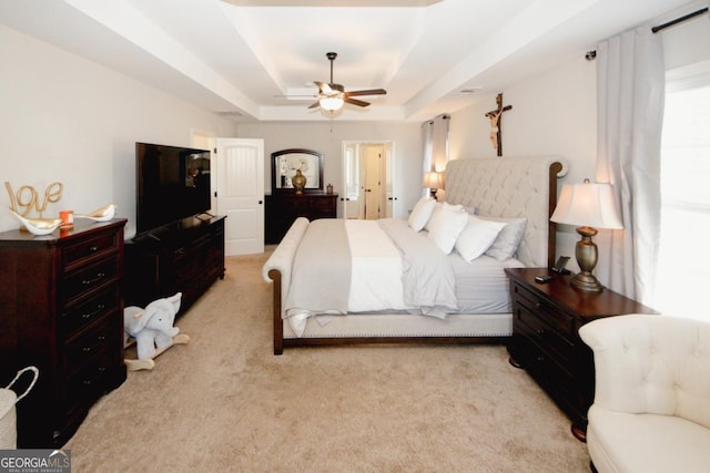 bedroom featuring a ceiling fan, a raised ceiling, and light carpet