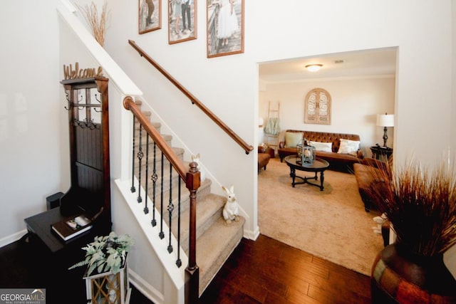 stairway with baseboards, wood finished floors, and ornamental molding