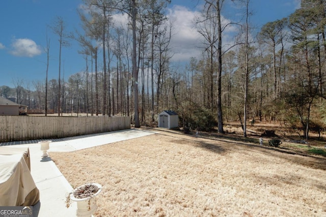 view of yard with fence, a storage unit, and an outbuilding