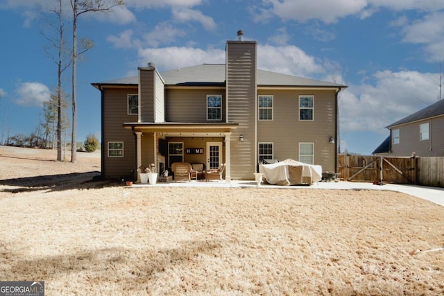 back of house with a chimney, a gate, fence, and a patio