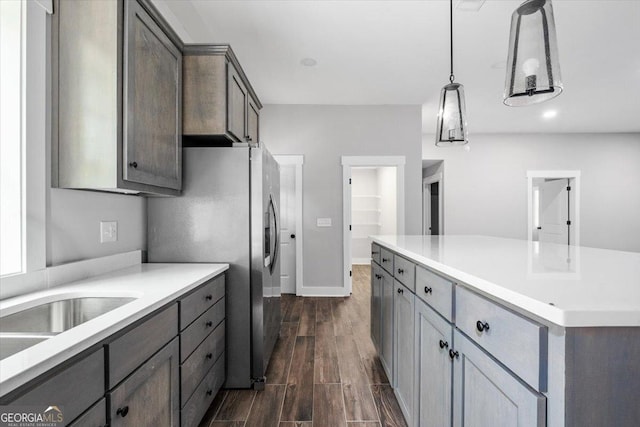 kitchen with dark wood-style floors, light countertops, stainless steel refrigerator with ice dispenser, and decorative light fixtures