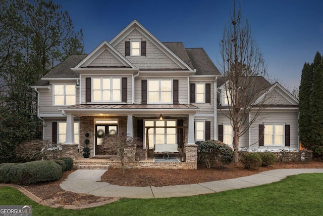 craftsman inspired home featuring a standing seam roof, a porch, and brick siding