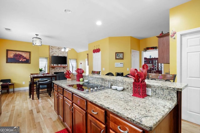 kitchen featuring visible vents, a kitchen island, open floor plan, hanging light fixtures, and black electric cooktop