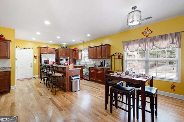 kitchen with a breakfast bar, stainless steel appliances, hanging light fixtures, a sink, and a kitchen island