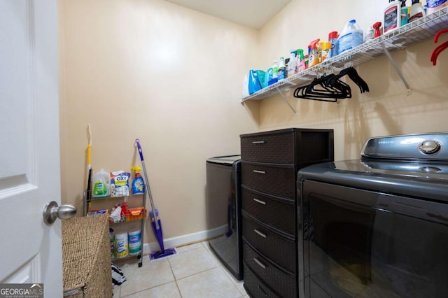 laundry area with laundry area, light tile patterned flooring, washing machine and dryer, and baseboards