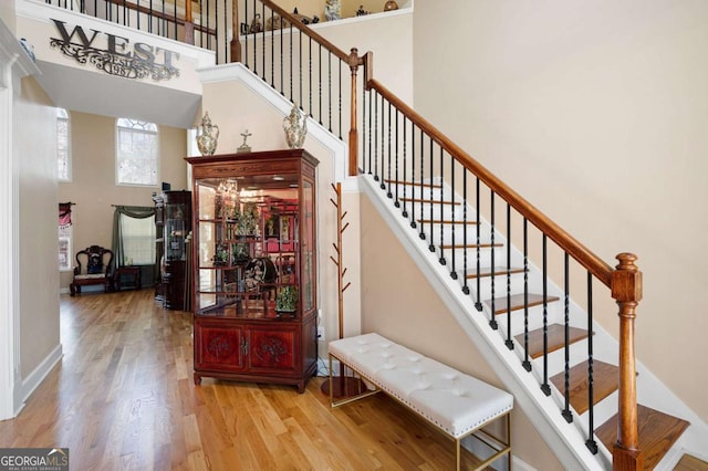 stairway with baseboards, a high ceiling, and wood finished floors