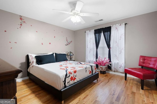 bedroom with light wood-style floors, visible vents, ceiling fan, and baseboards
