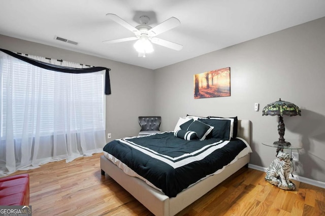 bedroom featuring a ceiling fan, light wood-type flooring, visible vents, and baseboards