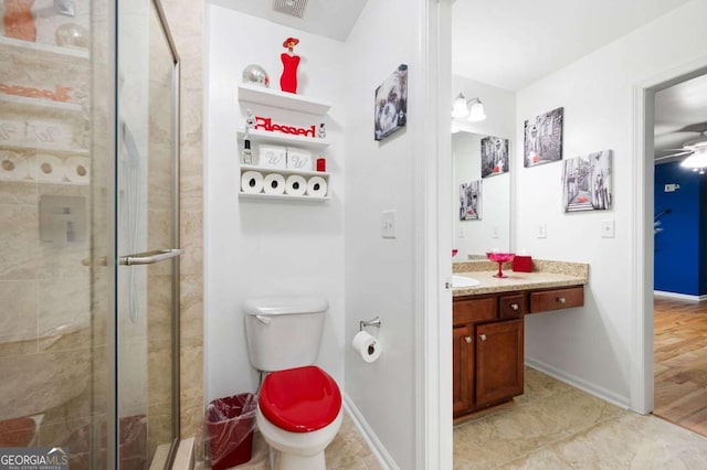 bathroom with toilet, a shower stall, vanity, and baseboards