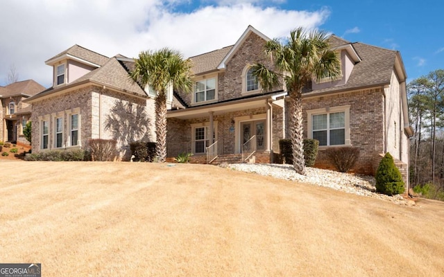 view of front of home with brick siding, a front lawn, and a shingled roof