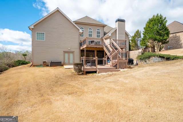 rear view of property with a chimney, a lawn, a deck, cooling unit, and stairs