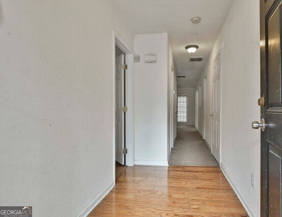 corridor with light wood-type flooring and visible vents