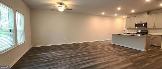 kitchen with dark wood-type flooring, a sink, white cabinetry, appliances with stainless steel finishes, and an island with sink