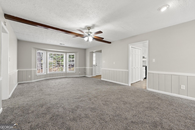 spare room featuring ceiling fan, wainscoting, a textured ceiling, and carpet