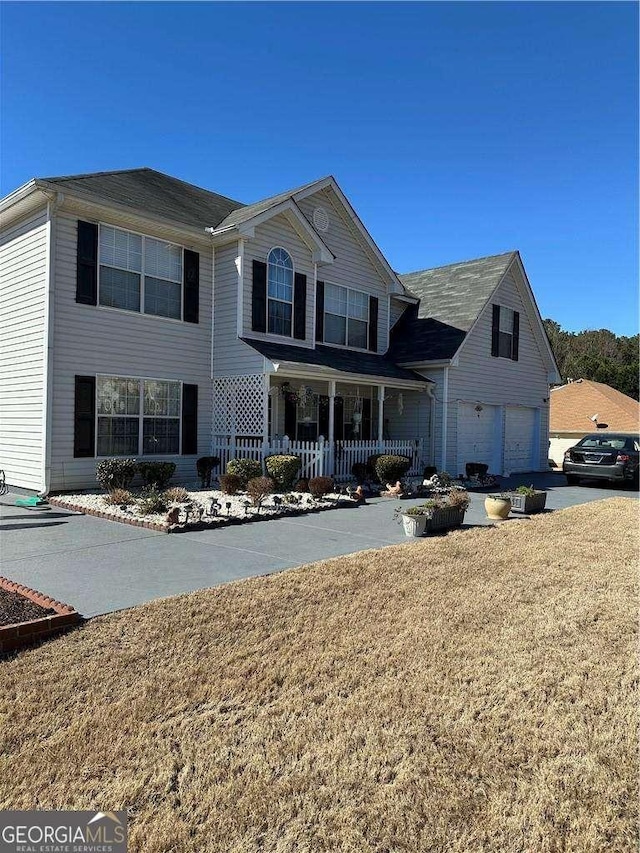 traditional home featuring a garage, covered porch, and a front yard