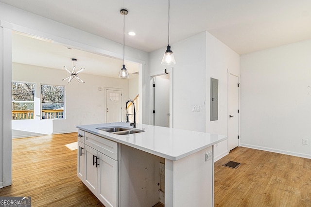 kitchen featuring pendant lighting, light countertops, open floor plan, a sink, and an island with sink