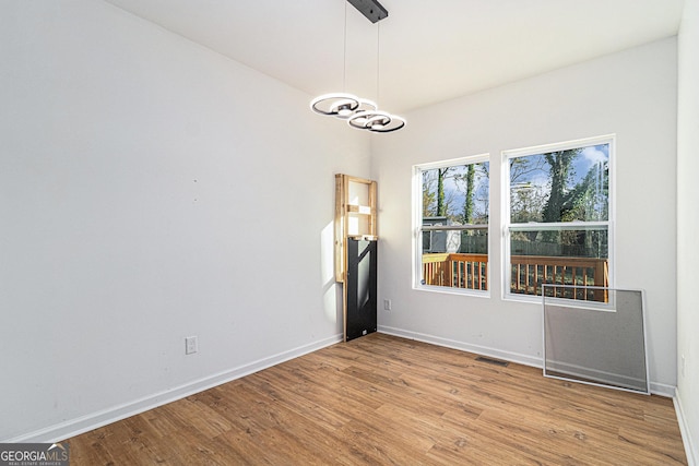 spare room with light wood-style flooring, visible vents, and baseboards