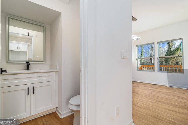 bathroom with toilet, baseboards, wood finished floors, and vanity