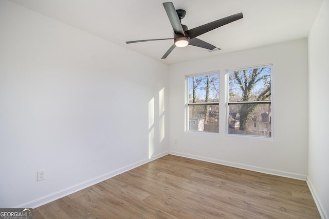 spare room with baseboards, ceiling fan, visible vents, and light wood-style floors