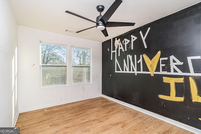 unfurnished room featuring baseboards, visible vents, ceiling fan, and wood finished floors