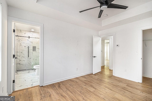 unfurnished bedroom featuring light wood-type flooring, a closet, ensuite bath, and baseboards