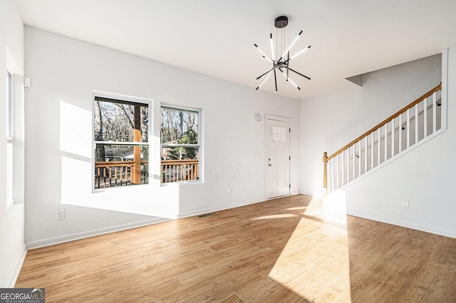 foyer with stairs, baseboards, wood finished floors, and a chandelier