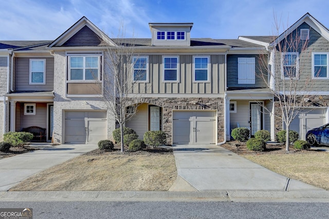 multi unit property featuring driveway, stone siding, board and batten siding, and an attached garage